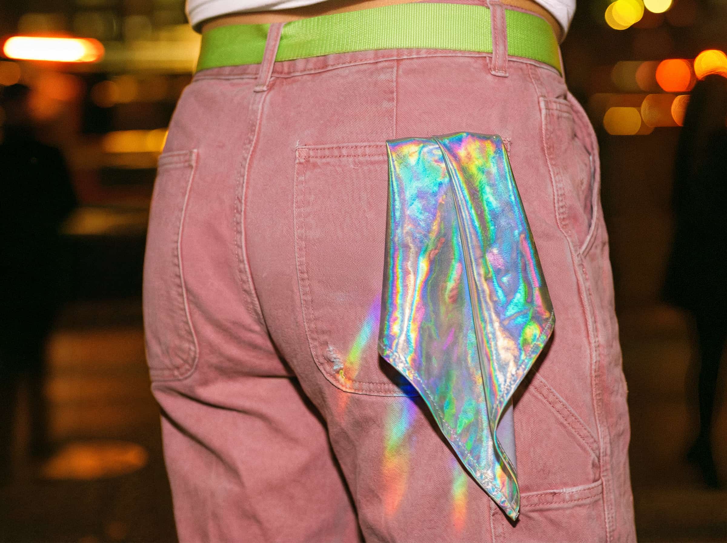 A person from behind wearing dusty pink pants with a holographic hanky in their back pocket.